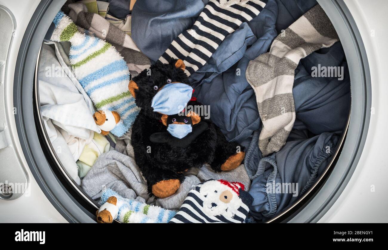 Ours en peluche et son bébé avec masque protecteur sur le point d'être lavé dans la machine à laver avec l'expression de démission pour une éventuelle infection par le coronavir Banque D'Images