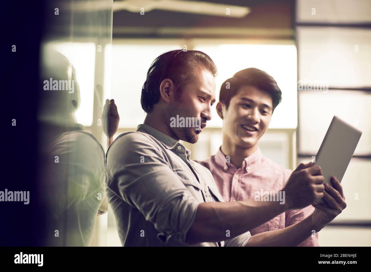 deux hommes d'affaires asiatiques travaillant ensemble au bureau en regardant la tablette numérique Banque D'Images