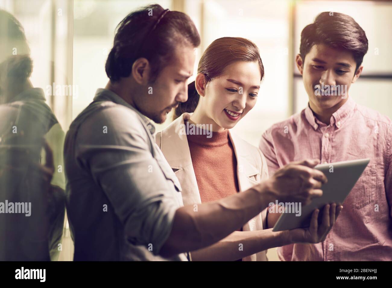 trois jeunes entrepreneurs asiatiques travaillant ensemble au bureau à la recherche d'une tablette numérique Banque D'Images