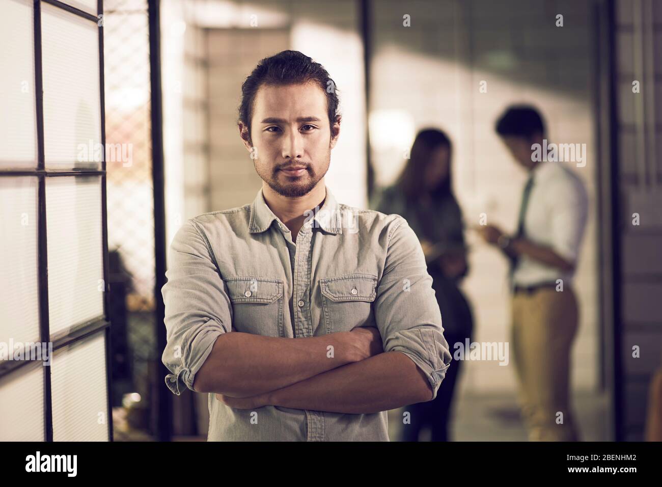 portrait d'un jeune entrepreneur asiatique prospère confiant debout dans les bras de bureau croisé Banque D'Images