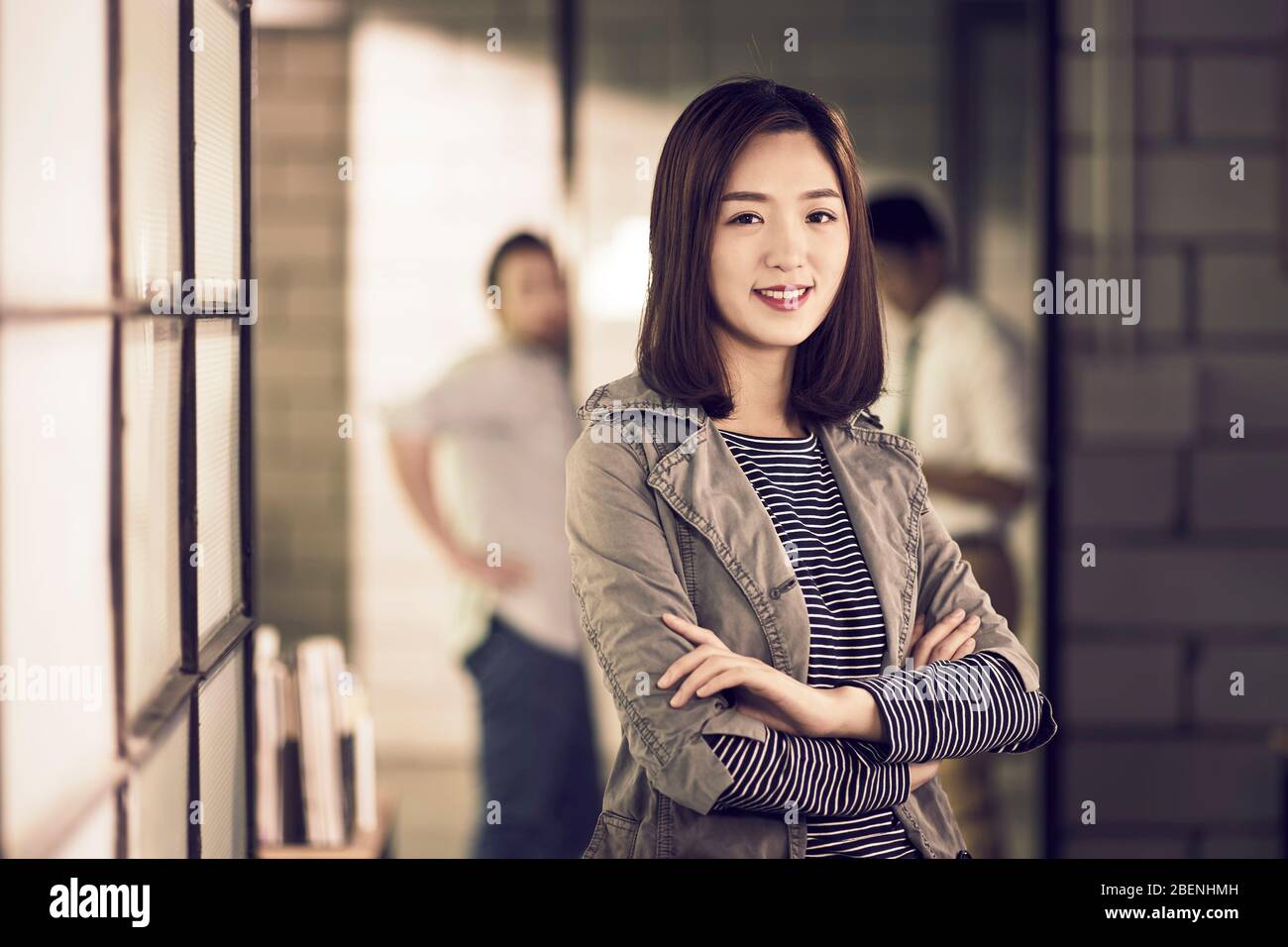 portrait d'un jeune entrepreneur asiatique d'affaires confiant et réussi debout dans les bras de bureau croisé Banque D'Images