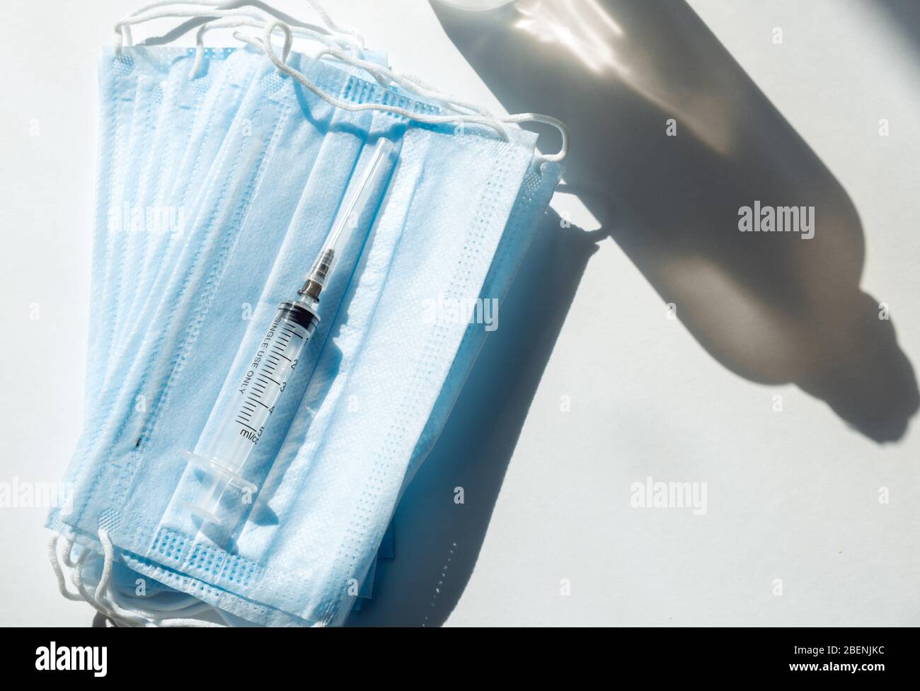 Seringue avec vaccin bleu et ampoule sur le masque médical. Fond blanc Banque D'Images
