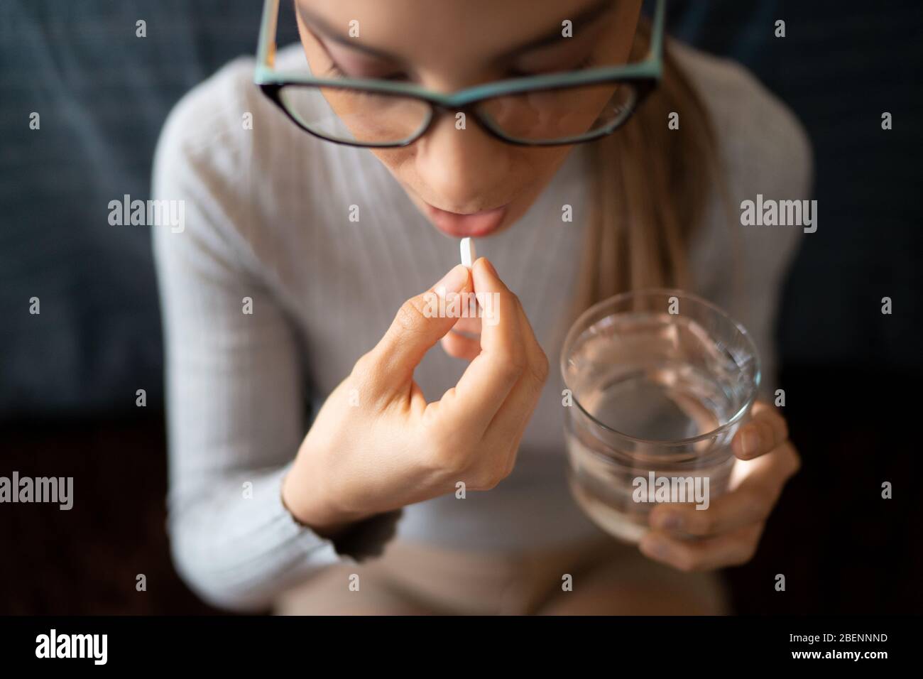 Une jeune Sick White Woman à la maison avaler ses pilules de traitement  médical avec un verre d'eau Photo Stock - Alamy