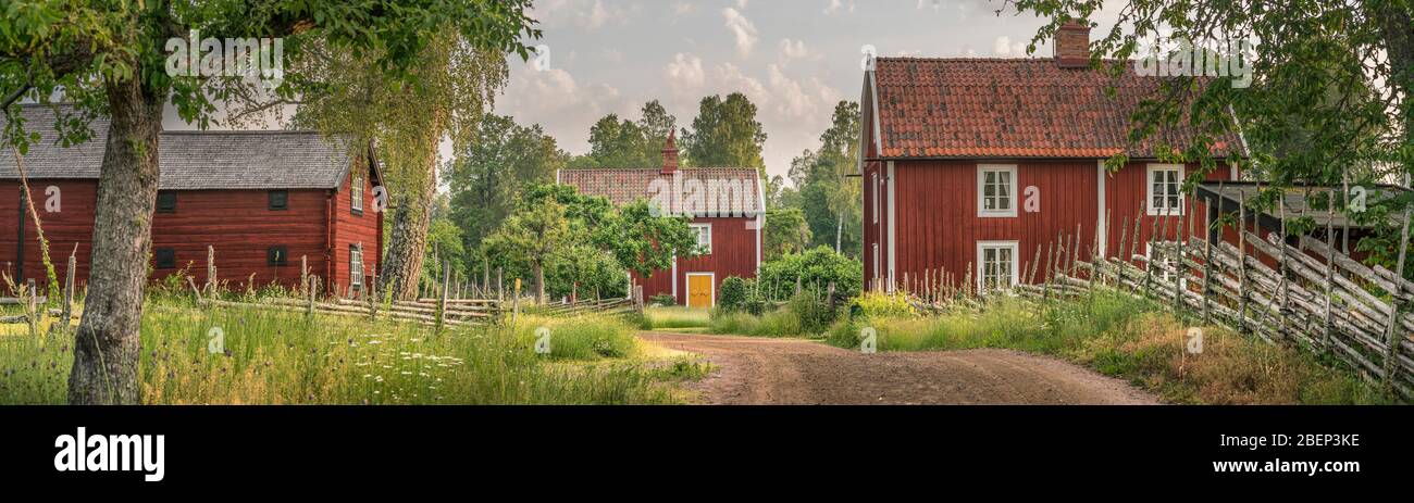 Petite route de campagne et vieux cottages traditionnels rouges dans un paysage rural au village Stensjo by. Oskarshamn, Smaland, Suède, Scandinavie Banque D'Images