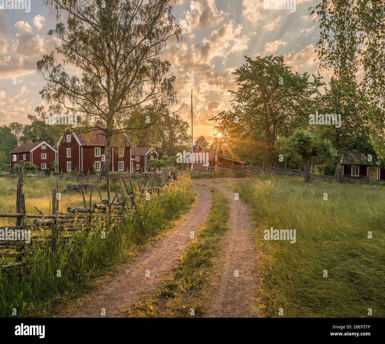 Petite route de campagne et vieux cottages traditionnels rouges au lever du soleil dans un paysage rural, le village Stensjo by. Oskarshamn, Smaland, Suède, Scandinavie Banque D'Images
