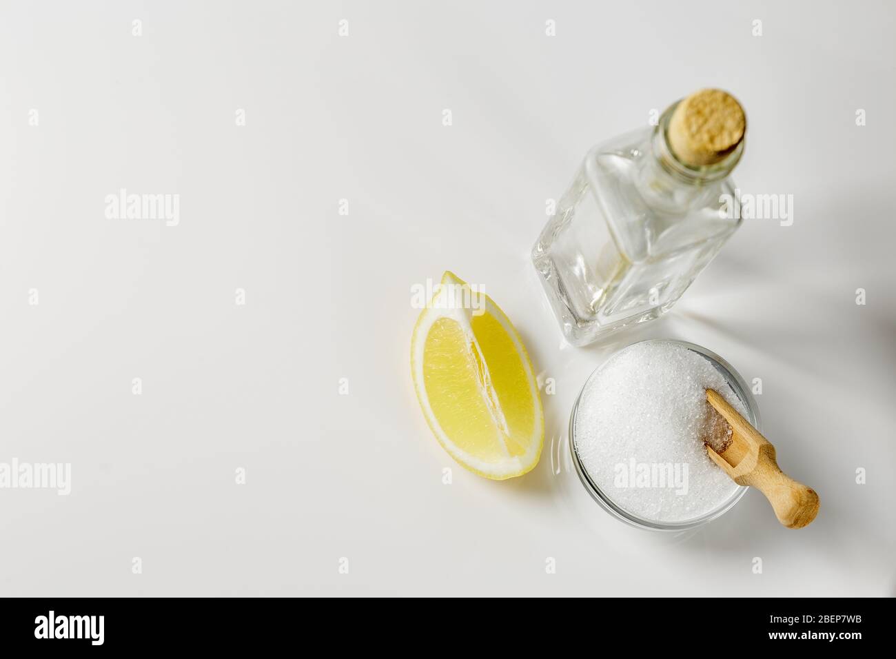 Acide citrique dans un petit bol en verre, vinaigre blanc dans une bouteille et une tranche de citron sur fond lumineux, ingrédients de produit de nettoyage Banque D'Images