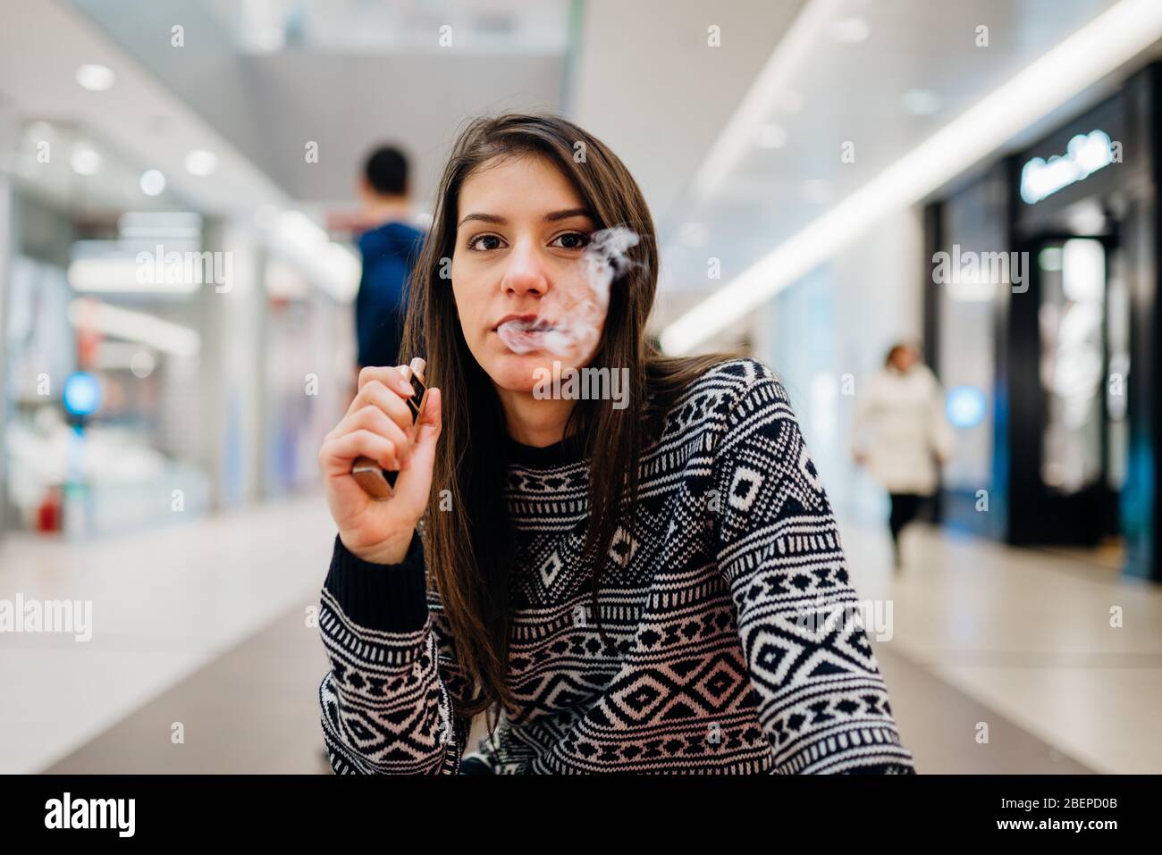 Jeune femme à l'aide de la cigarette électronique pour fumer dans les lieux publics.restriction fumée,interdiction de fumer.En utilisant l'appareil avec des liquides aromatisés vaping.E-juice vapin Banque D'Images