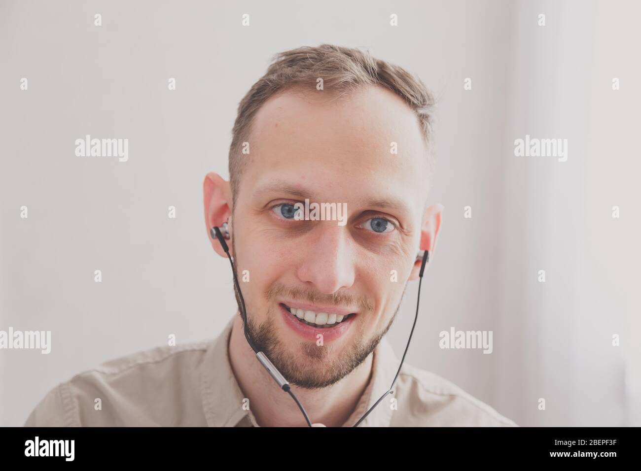 Jeune homme souriant et sympathique avec casque pour la communication en ligne en tant que support client virtuel professionnel ou service à la clientèle ou pendant Banque D'Images