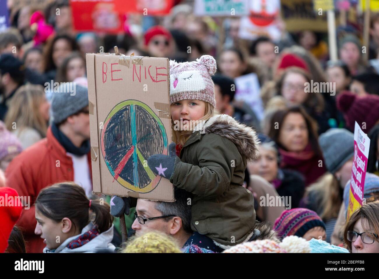 Jeune fille assise sur les épaules d'un homme et tenant une lecture de signe "Be Nice", à la Marche des femmes 2017, Londres Banque D'Images