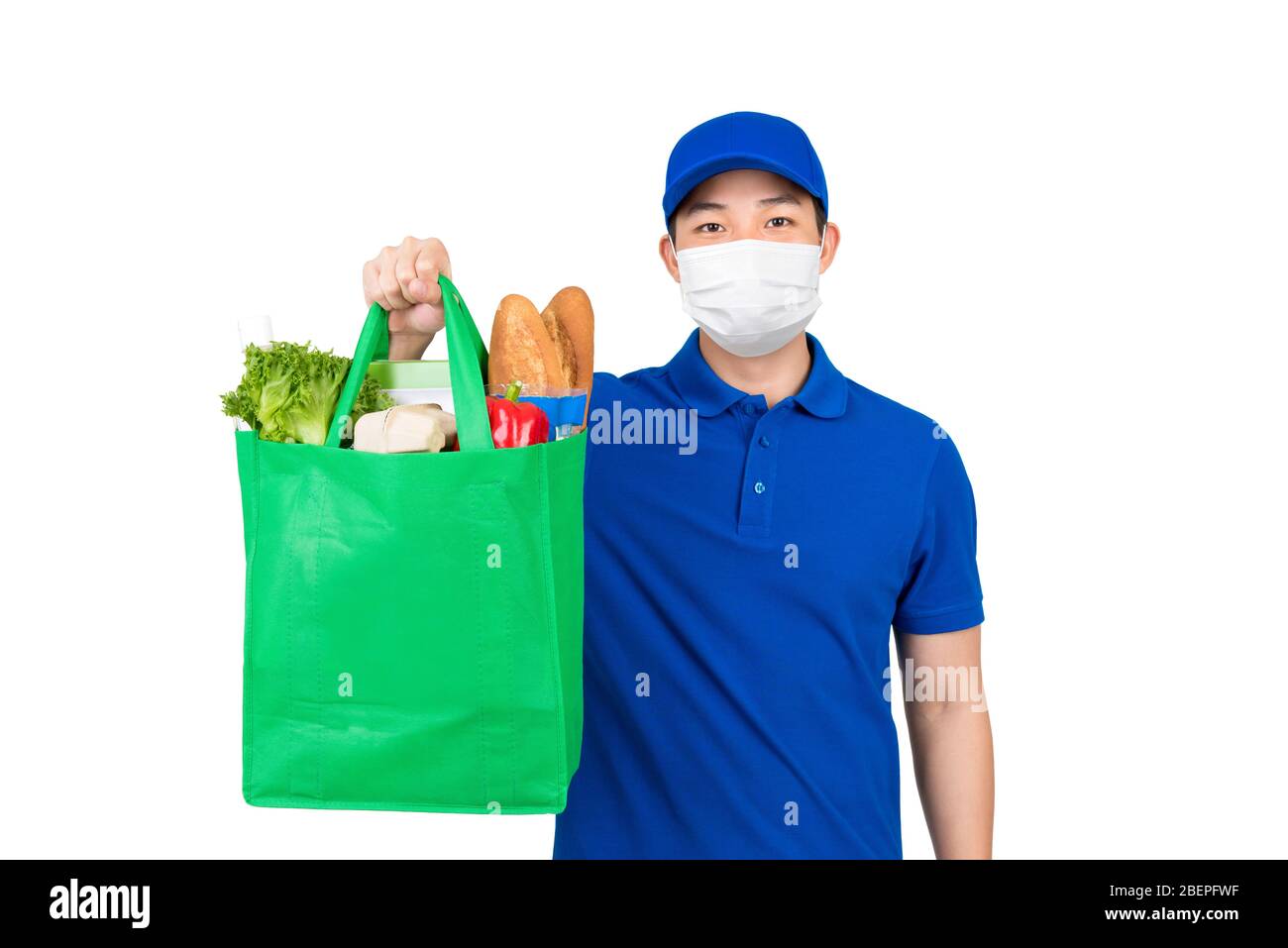 Homme hygiénique portant un masque médical tenant un sac de shopping d'épicerie de supermarché offrant un service de livraison à domicile isolé dans un fond blanc Banque D'Images