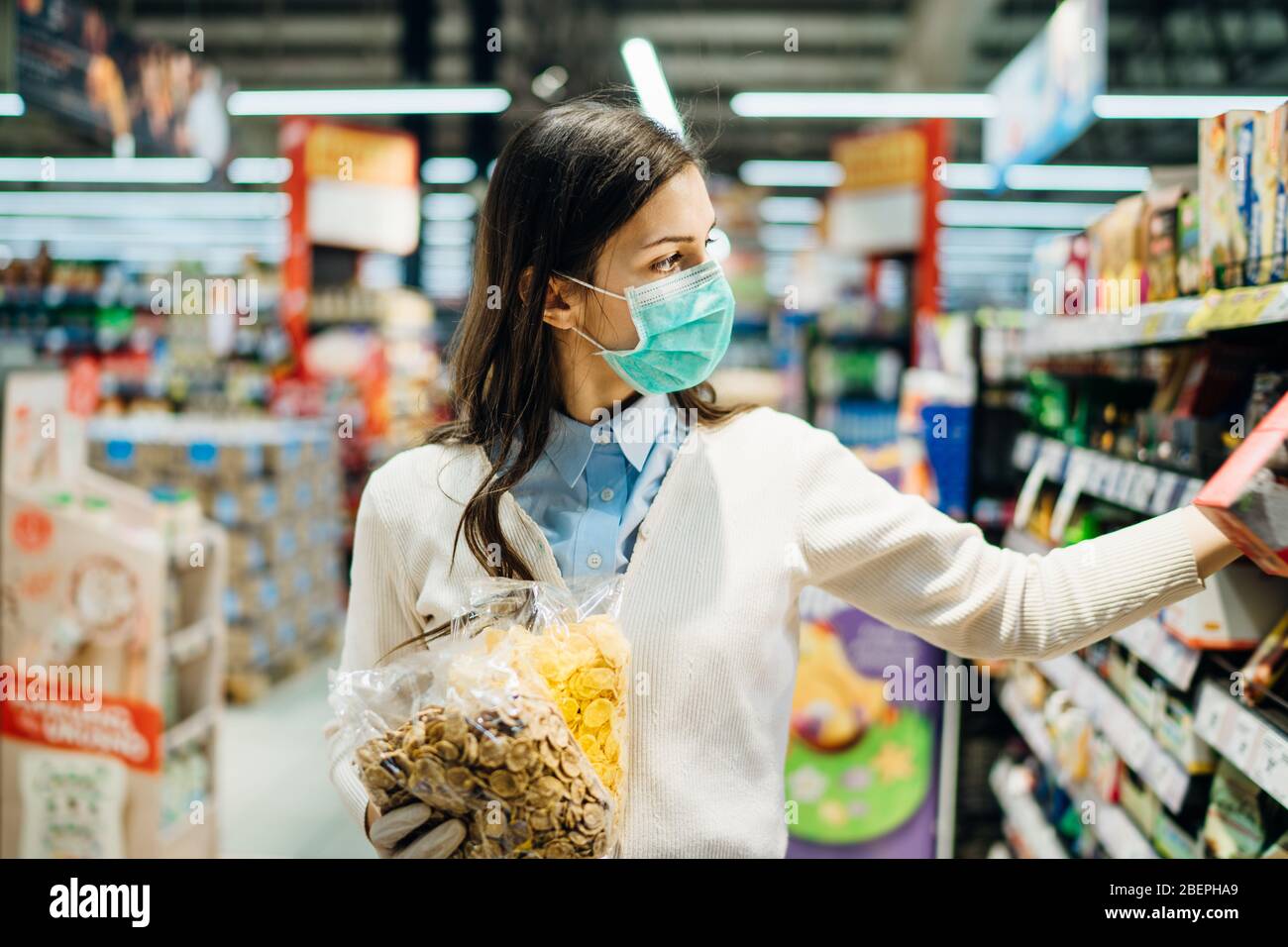 Faire des achats en toute sécurité de cabas avec masque pour les provisions en raison de la pandémie de coronavirus dans une épicerie en stock.COVID-19 achat d'un supermarché alimentaire.non périssables f Banque D'Images