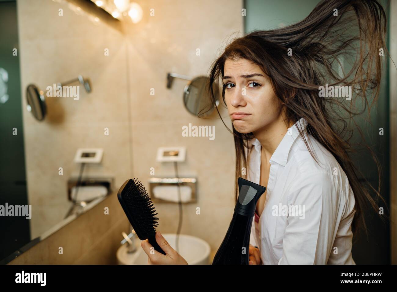 Femme faisant son coiffage avec une brosse à la maison.Bad hair day.routine quotidienne de préparation de coiffure.dégâts de chaleur, extrémités fendues, perte sèche de cheveux.se préparer Banque D'Images