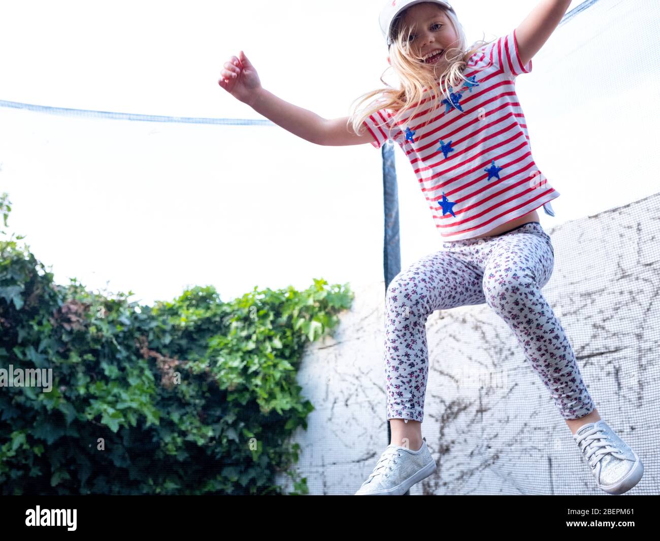 Une jeune fille de quatre ans saute sur un trampoline dans son jardin urbain à Londres, au Royaume-Uni Banque D'Images