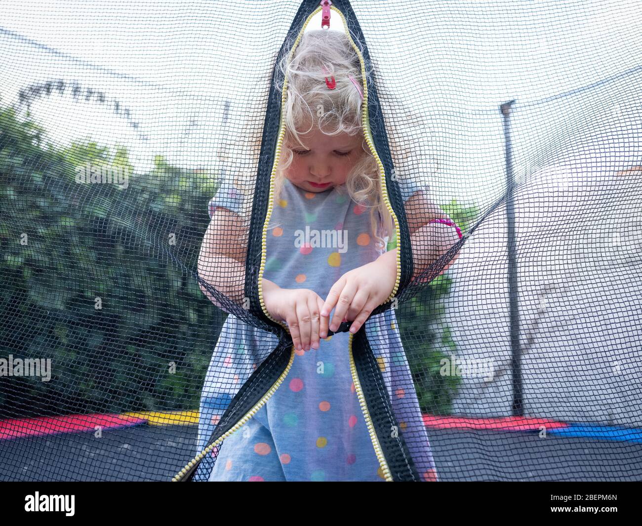 Une fille de deux ans (près de trois ans) à l'entrée de son trampoline de jardin. Banque D'Images
