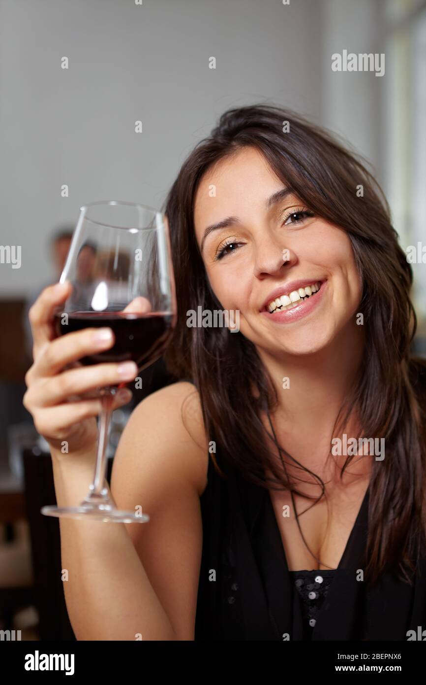 Une femme heureuse avec un verre de vin rouge dans un restaurant Banque D'Images