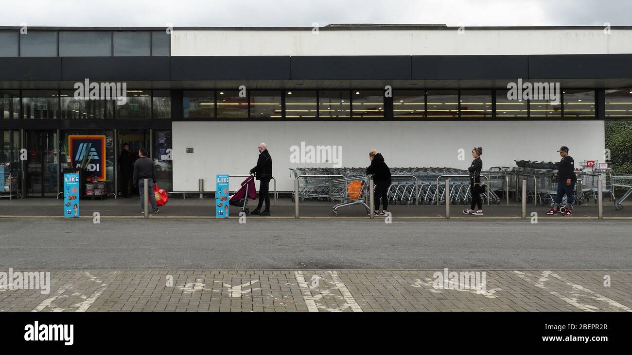 Les clients font la queue devant un supermarché, à 2 mètres de distance, dans le cadre de l'épidémie de coronavirus distancing social Banque D'Images