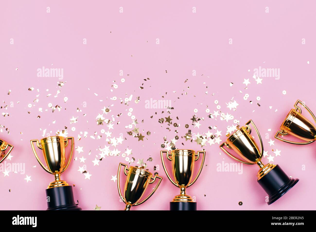 Coupes Golden Winner avec des taches sur un fond rose avec espace de copie. Concept festif. Style plat. Banque D'Images