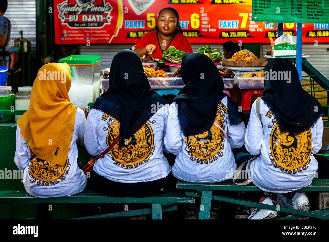 Jeunes femmes indonésiennes manger de la nourriture à UN Street Food Stall, Malioboro Street, Yogyakarta, Indonésie. Banque D'Images