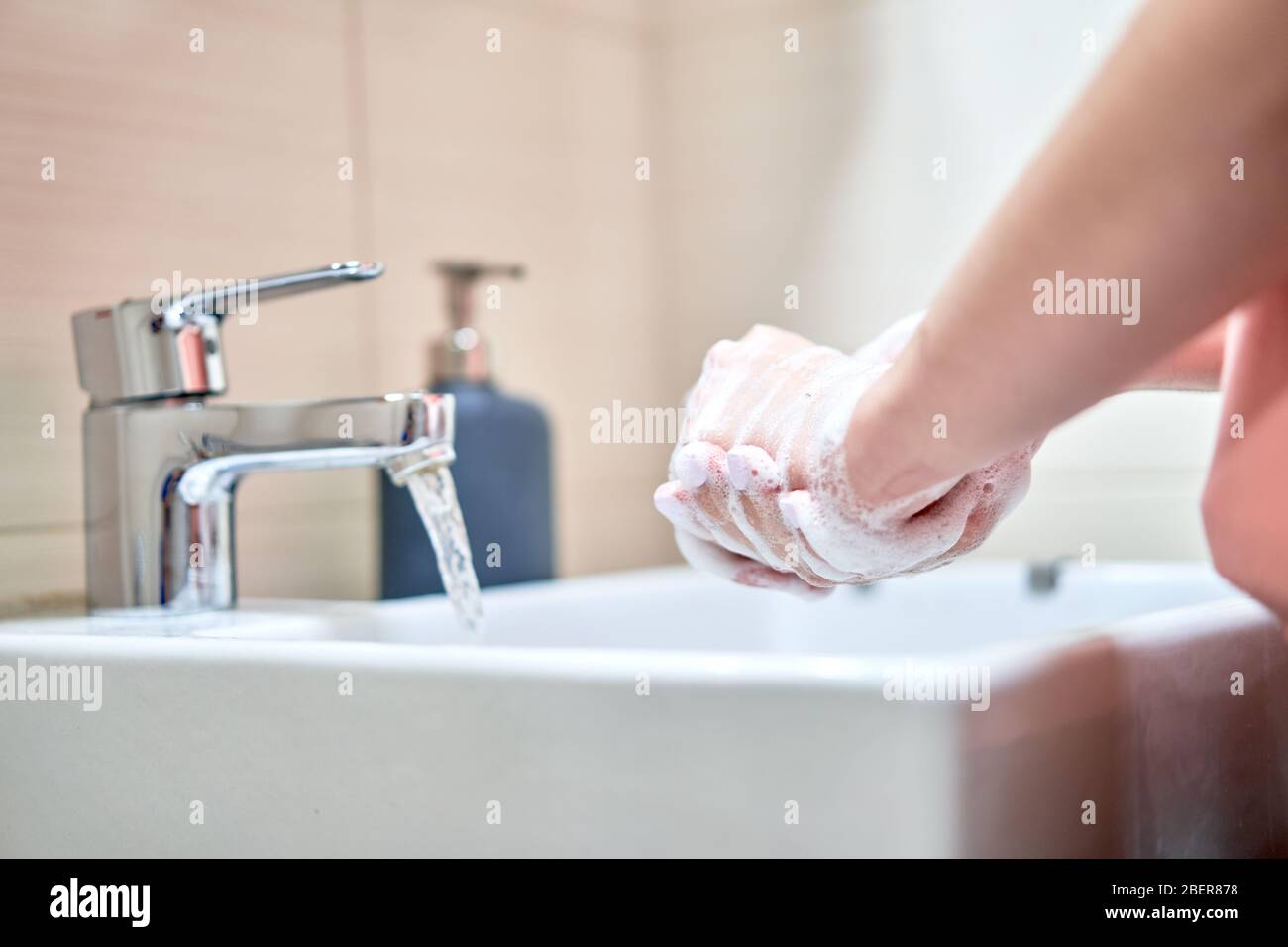 Lavage des mains avec du savon sous l'eau dans la salle de bains Banque D'Images