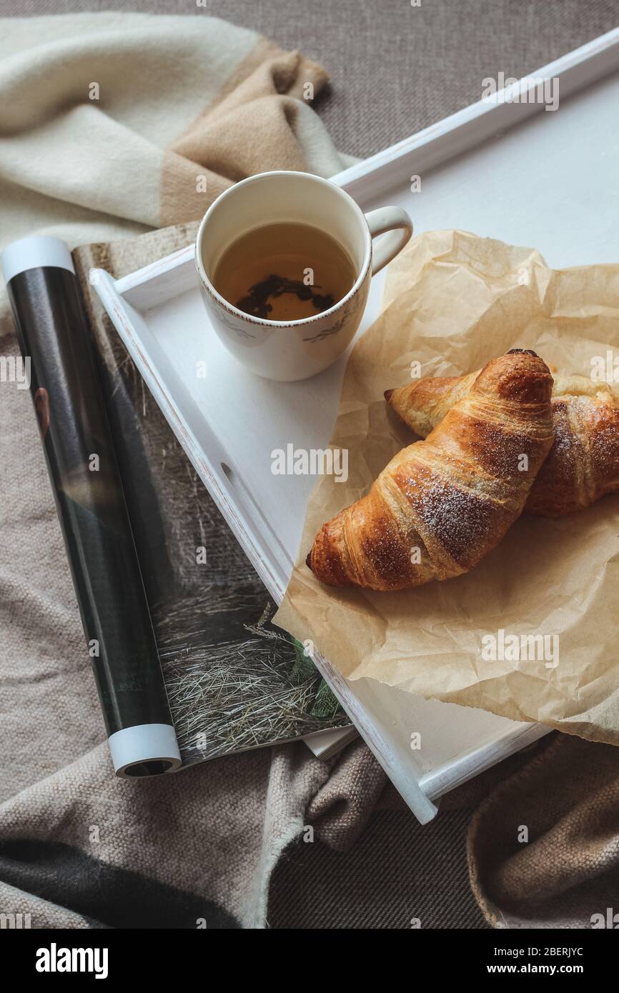Une tasse de thé et de croissants est servie sur un plateau pour le petit-déjeuner du week-end Banque D'Images