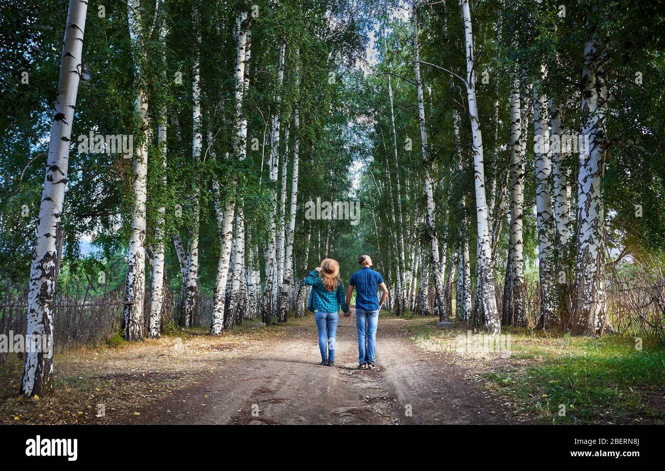 Couple heureux dans les shirts sur la route dans les bois de bouleau, au Kirghizistan. Date romantique dans la forêt. Banque D'Images