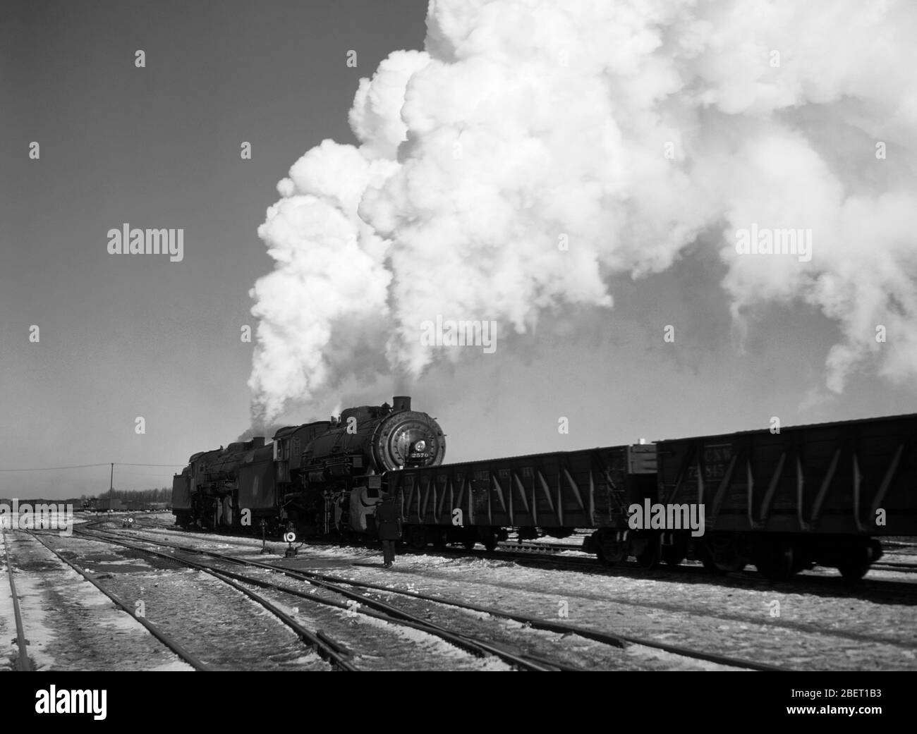Un train à vapeur dans une cour de train soufflant des nuages de fumée ciel haut. Banque D'Images