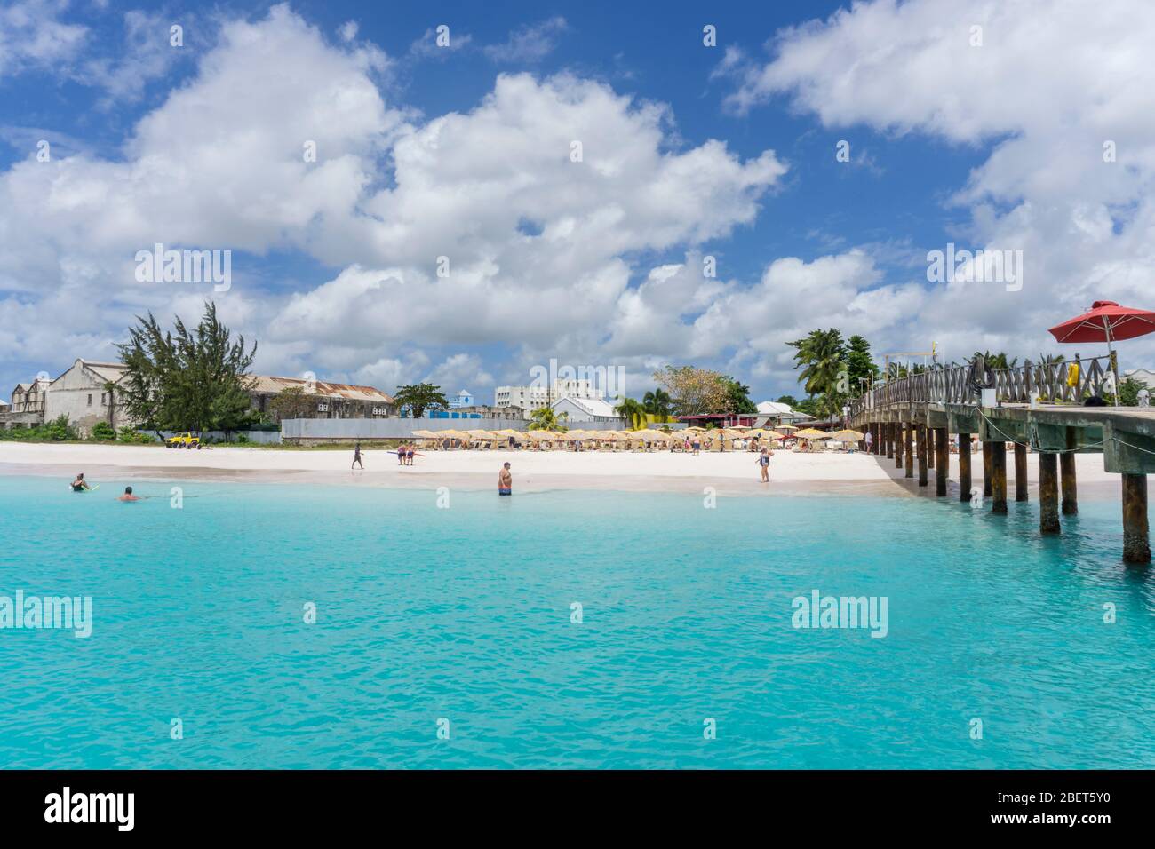 Les gens qui apprécient l'eau et la plage une journée chaude et ensoleillée au Boatyard, Bridgetown, Barbade Banque D'Images