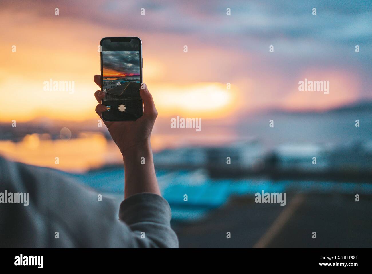 Tenez un smartphone en prenant une photo de la mer au coucher du soleil Banque D'Images