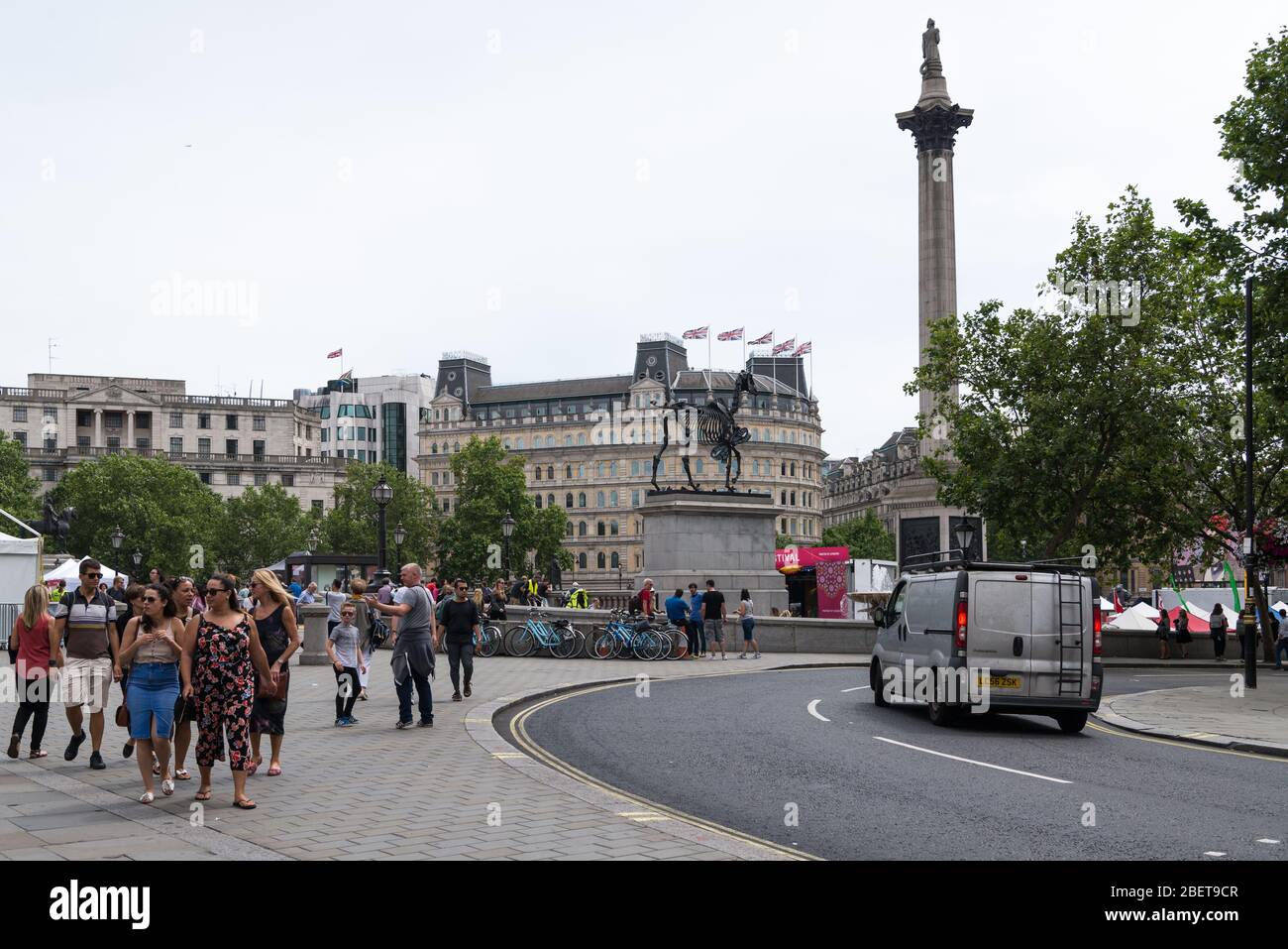 Touristes et touristes à Trafalgar Square, Londres, Angleterre, Royaume-Uni. La sculpture d'Hanns Haacke d'un squelette de cheval se dresse sur le quatrième plinthe. Banque D'Images