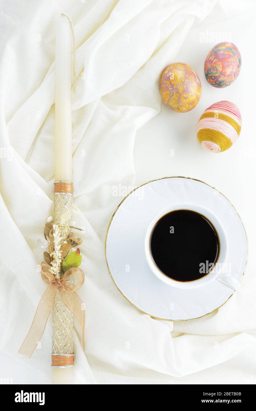 Bougie de Pâques, œufs de Pâques décorés et mug en porcelaine avec café noir Banque D'Images