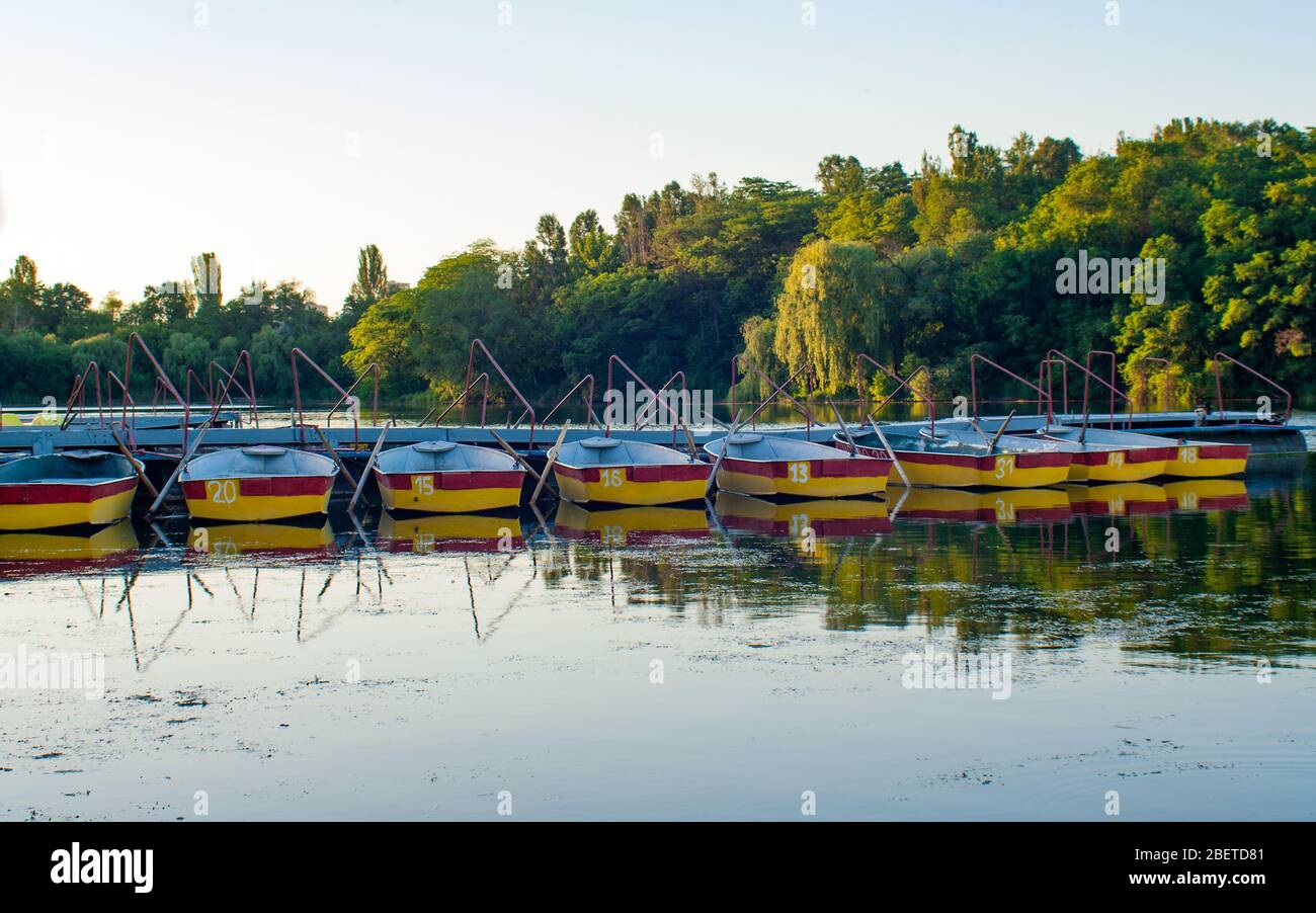 Des bateaux d'aviron de plaisir amarrés à la jetée dans l'étang du soir. Donetsk. Ukraine. Banque D'Images