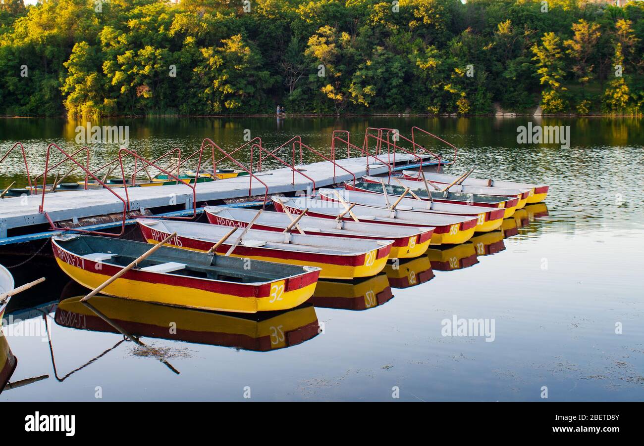 Des bateaux d'aviron de plaisir amarrés à la jetée dans l'étang du soir. Donetsk. Ukraine. Banque D'Images