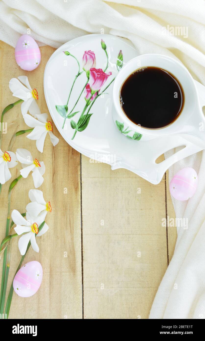 Œufs de Pâques décorés, tasse de café noir et fleurs de Narcisse de Poet sur table en bois Banque D'Images