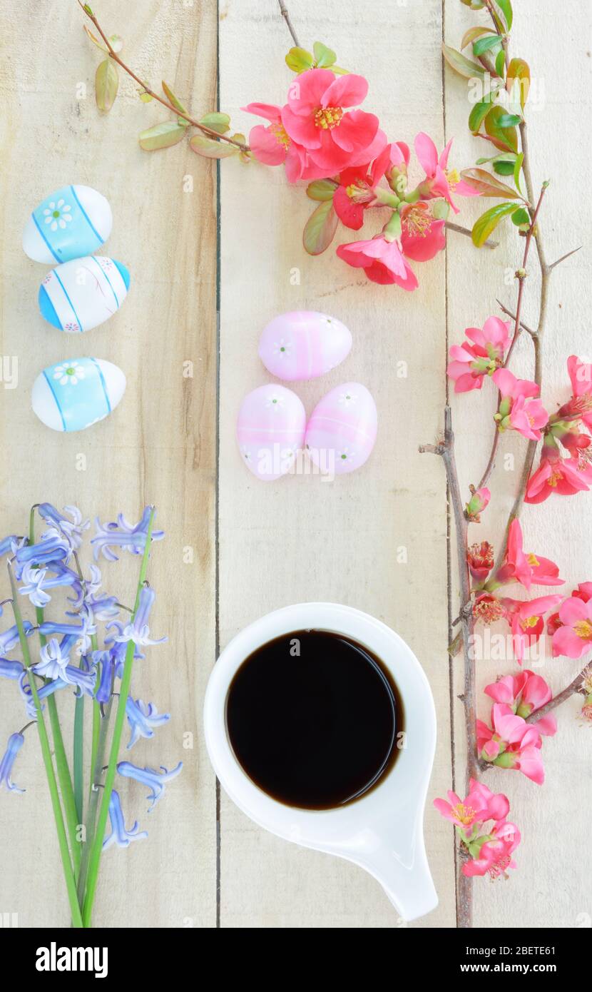 Petit bouquet de jacinthus, brunch de coing japonais, œufs de Pâques et une tasse de café noir sur table en bois Banque D'Images