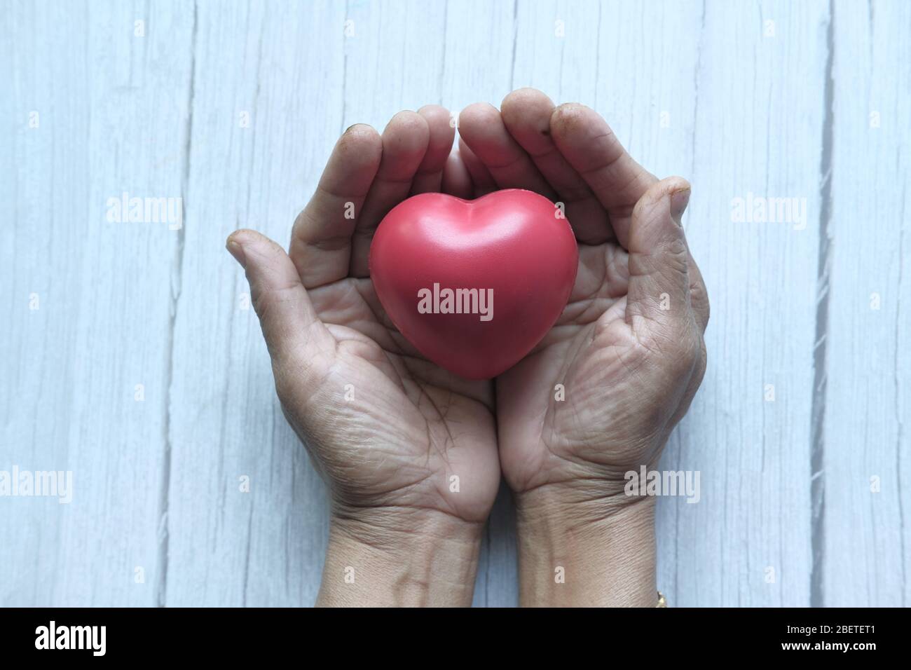 femme tenant le cœur rouge dans les mains sur table en bois . Banque D'Images