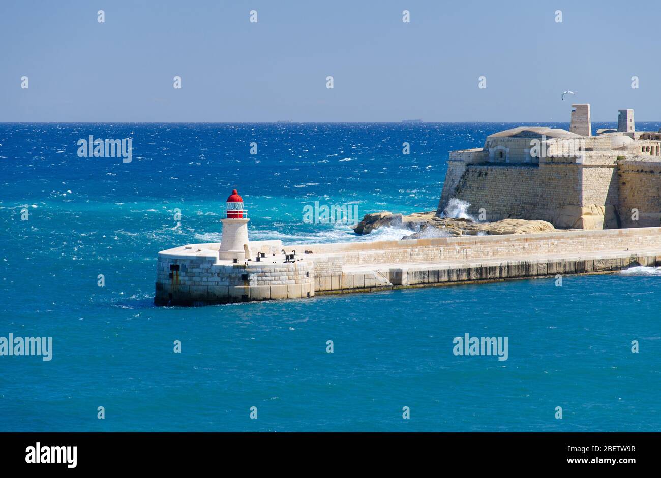 Vue sur l'entrée du port et l'ancienne Breakwater médiévale de Ricasoli est avec phare et fort Ricasoli vu de la Valette, Malte Banque D'Images