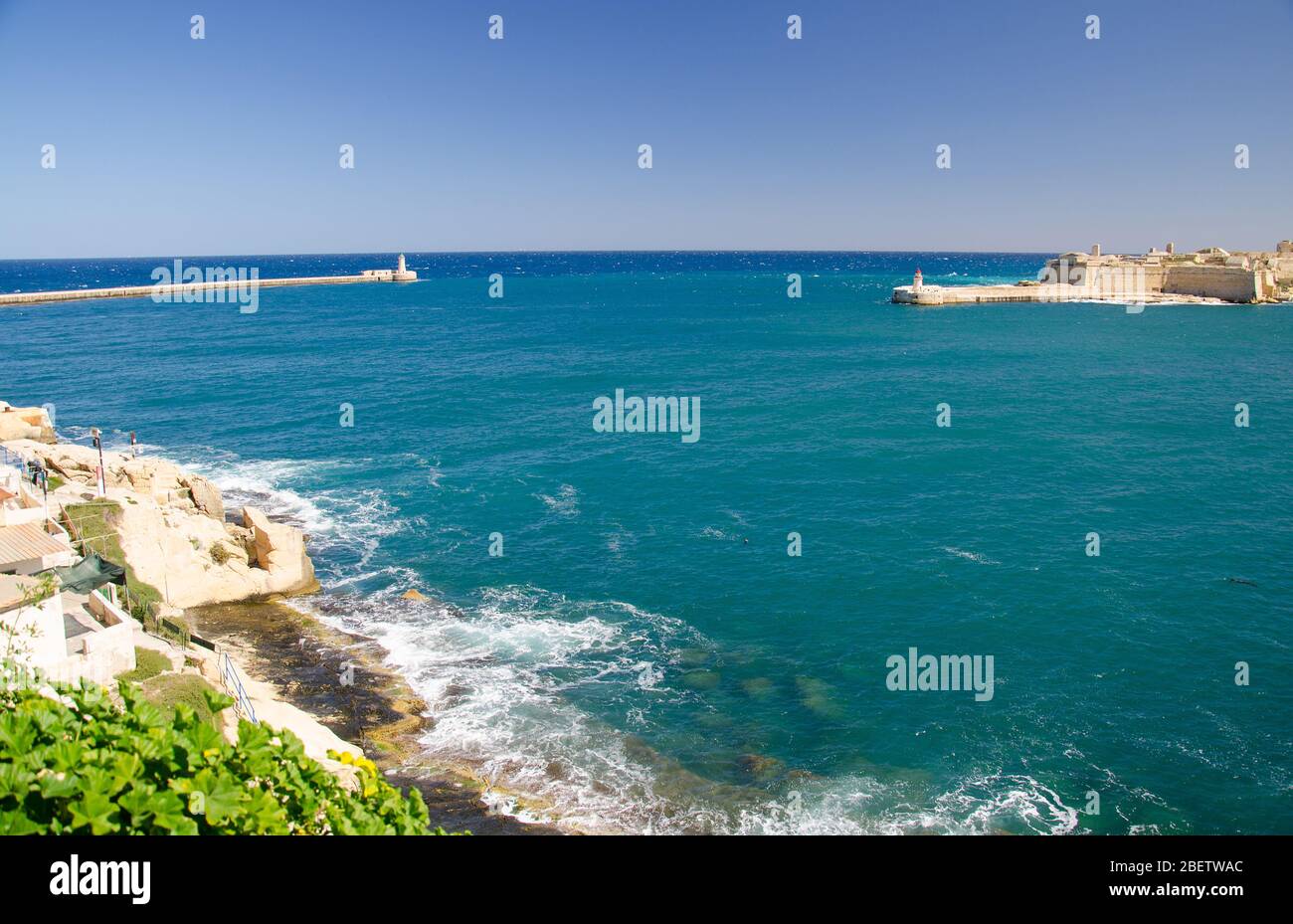 Vue sur l'entrée du port et l'ancienne Breakwater médiévale de Ricasoli est avec phare et fort Ricasoli vu de la Valette, Malte Banque D'Images