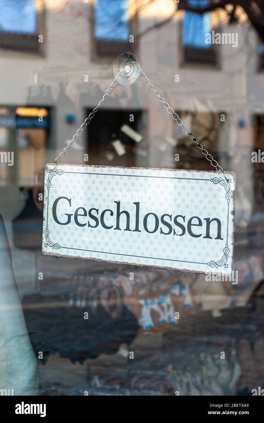 Fenêtre de boutique d'une boutique avec le signe 'fermé', en allemand, avec des écrans et le reflet de l'environnement en flou au moment de la Corona Covid- Banque D'Images