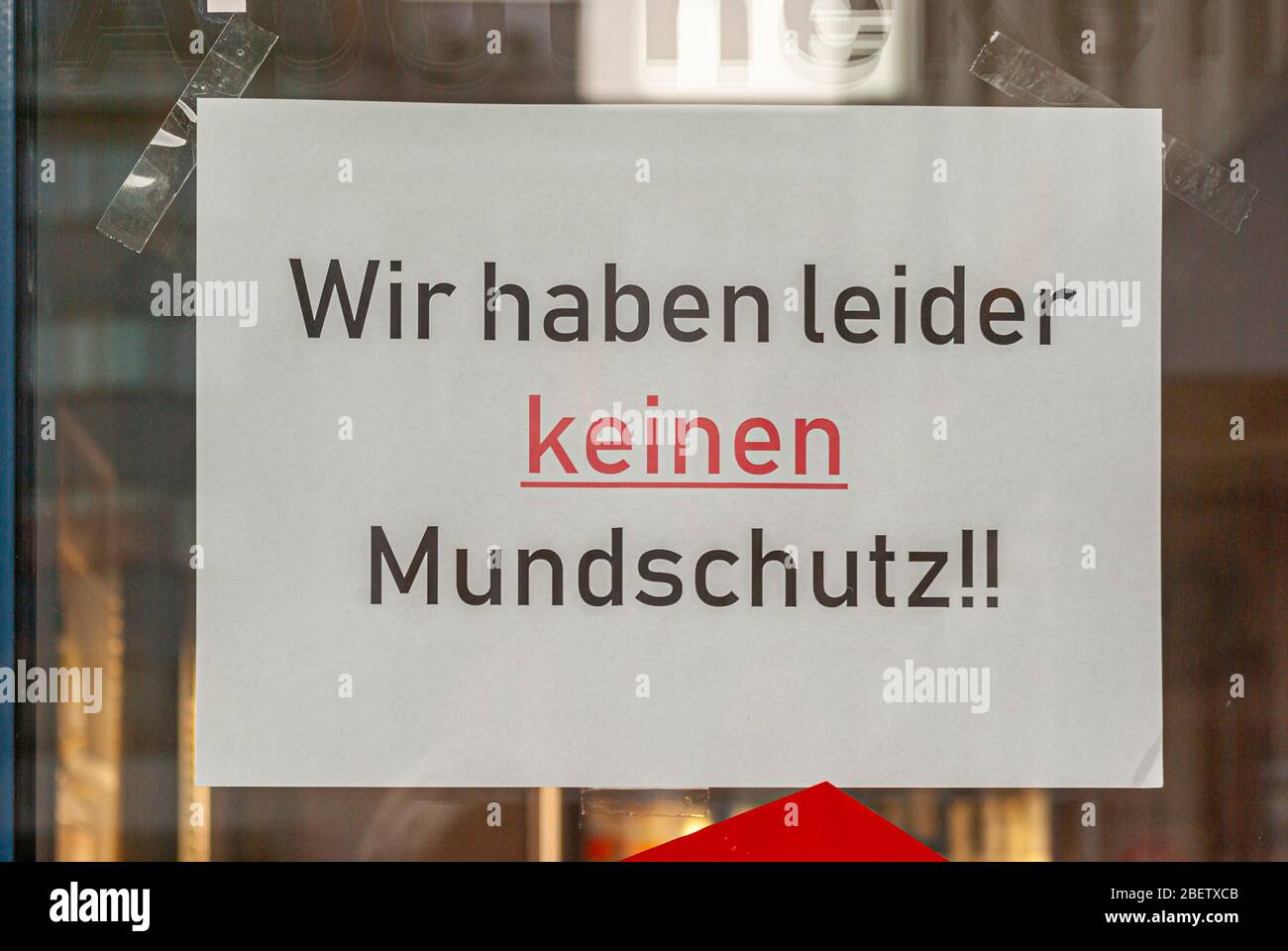 Fenêtre de magasin d'un magasin avec un signe disant "nous n'avons pas de garde-bouche", en allemand, avec des écrans et le reflet de l'environnement dans le flou à la Banque D'Images