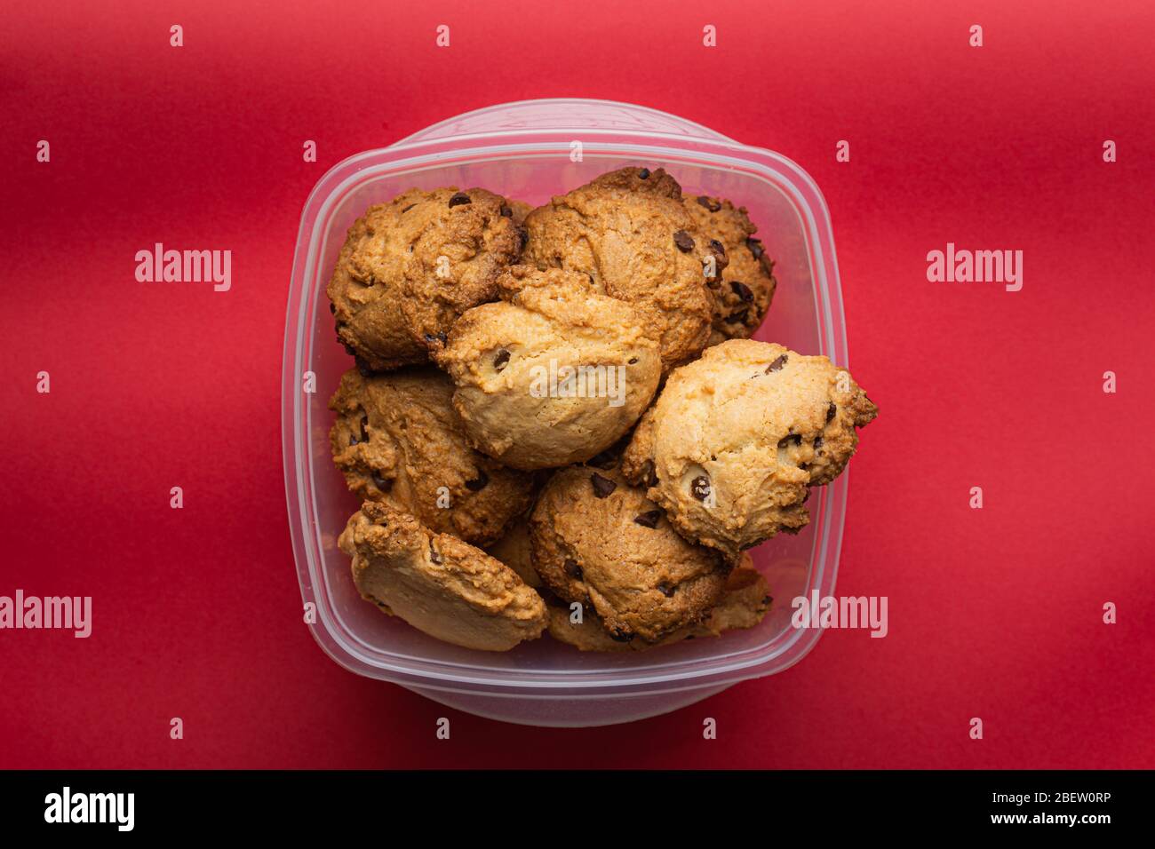 Cookies au chocolat faits maison sur un destinataire en plastique sur fond rouge Banque D'Images