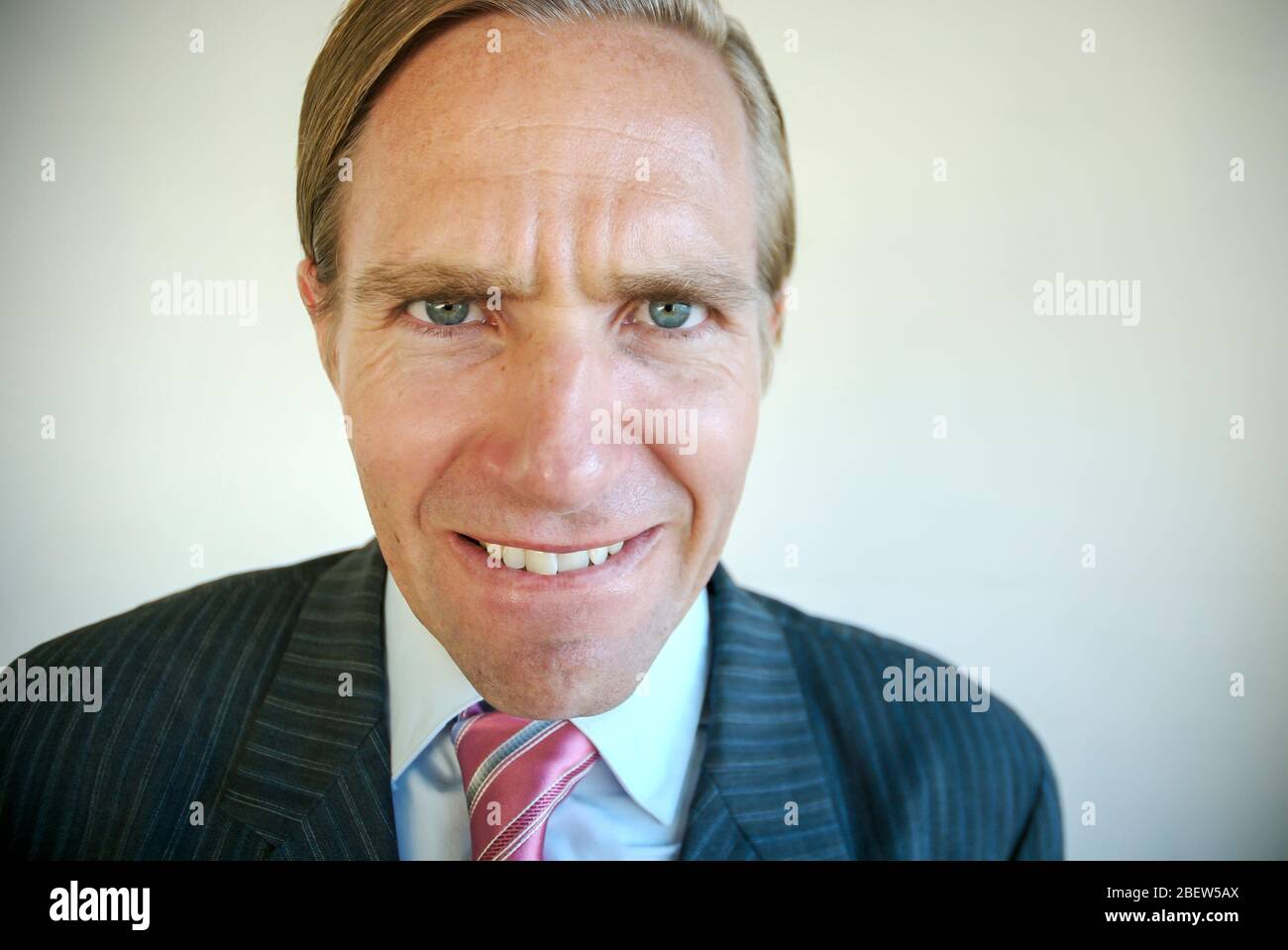 Homme d'affaires nerveux qui morde sa lèvre regardant la caméra avec une expression effrayée Banque D'Images