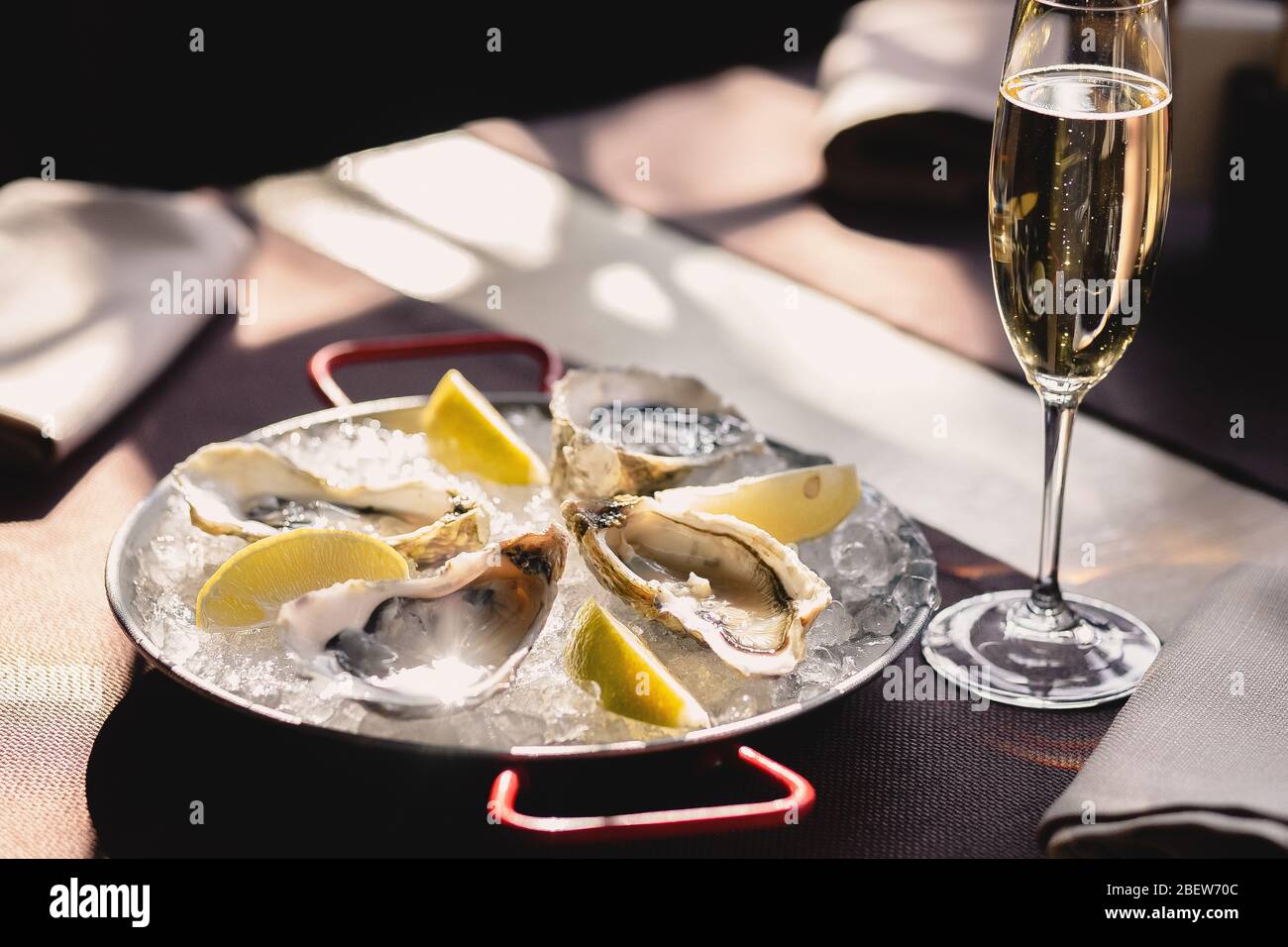 Assiette avec huîtres, citron et glace et un verre de champagne Banque D'Images