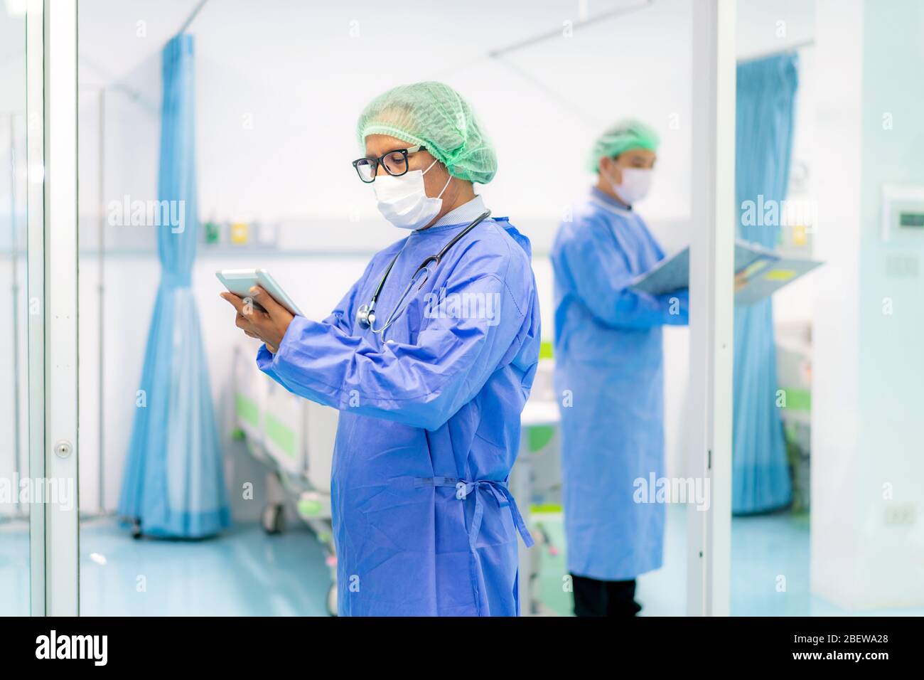 Médecin asiatique utilisant une tablette numérique et le personnel de l'équipe de médecins portant un masque facial à l'hôpital pendant l'éclosion de Coronavirus. Banque D'Images