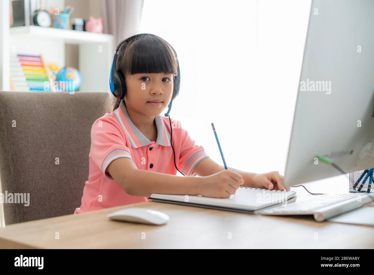 Asian girl étudiant vidéo conférence e-learning avec professeur sur ordinateur dans le salon à la maison. Homeschooling et l'apprentissage à distance, en ligne, l'éducation Banque D'Images