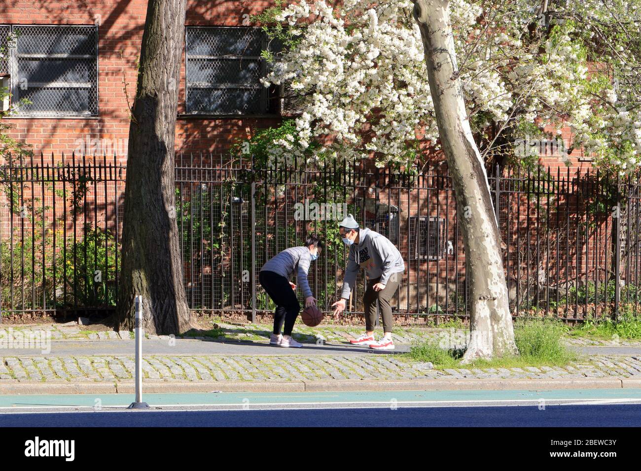 Un couple portant des masques dribble un basket sur un trottoir dans le Lower East Side à New York pendant le coronavirus... PLUS D'INFORMATIONS POUR LA LÉGENDE COMPLÈTE Banque D'Images
