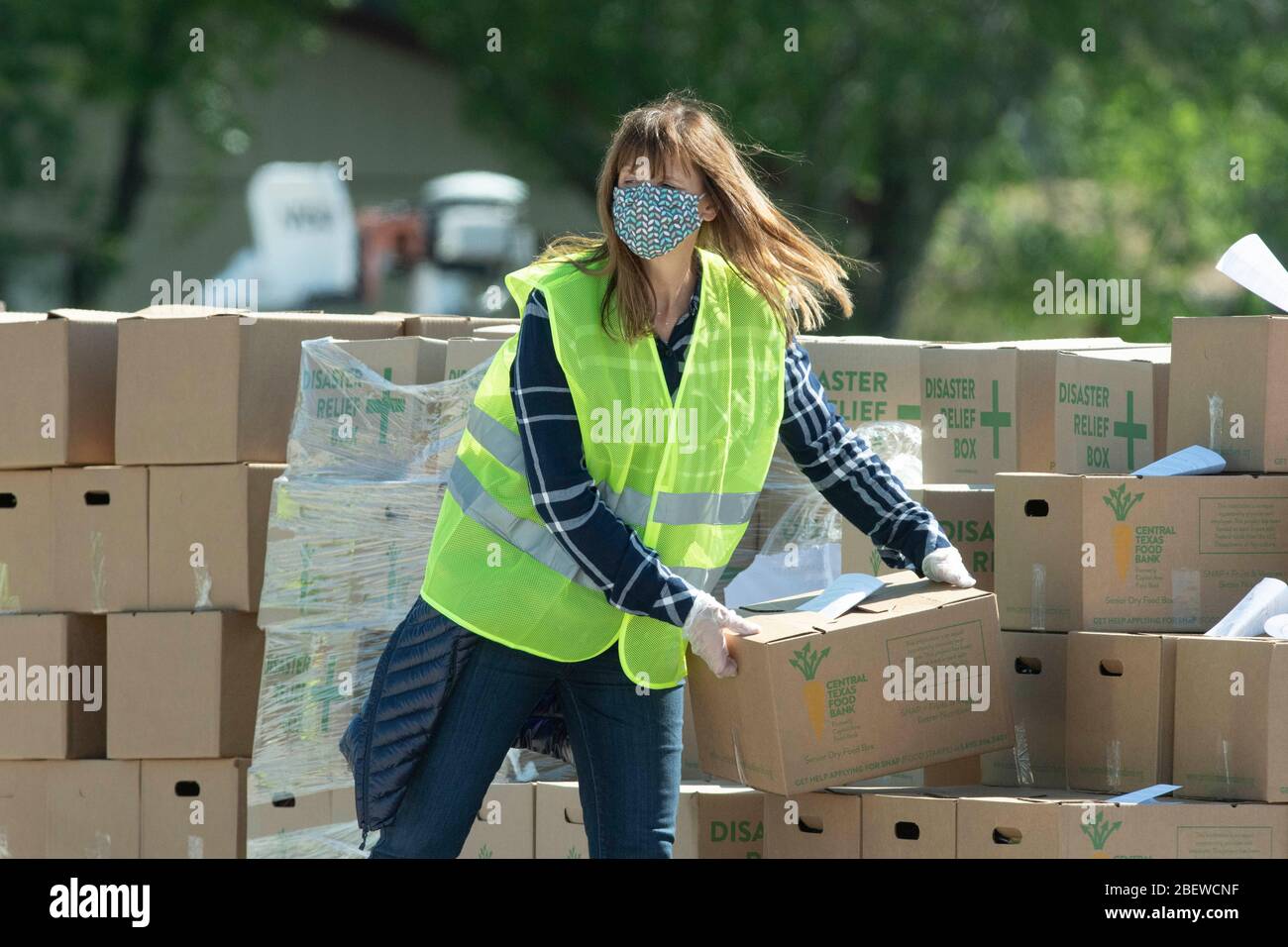 Central Texas Food Bank travaille de manière volontaire pour charger des boîtes de 28 livres d'agrafes dans des véhicules pendant un cadeau alimentaire à Austin, Texas. Près de 1 500 familles ont pris des boîtes en réponse à de nombreuses pertes d'emploi dues à la pandémie de coronavirus et aux retombées économiques générales du Texas Banque D'Images