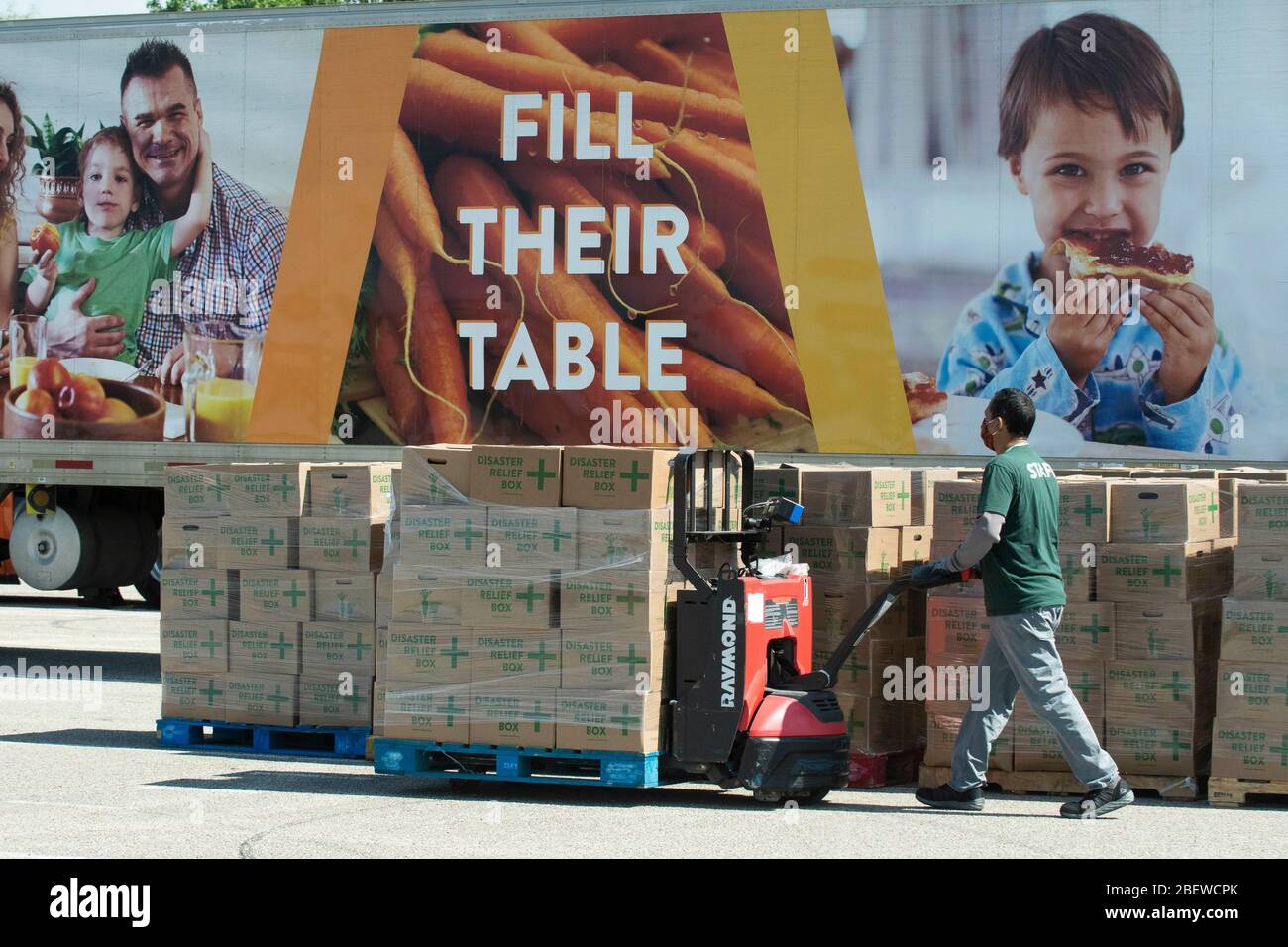 Central Texas Food Bank travaille de manière volontaire pour charger des boîtes de 28 livres d'agrafes dans des véhicules pendant un cadeau alimentaire à Austin, Texas. Près de 1 500 familles ont pris des boîtes en réponse à de nombreuses pertes d'emploi dues à la pandémie de coronavirus et aux retombées économiques générales du Texas. Banque D'Images