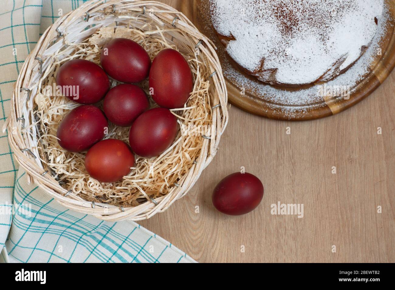 Directement au-dessus de la photo des œufs de Pâques dans le panier avec de la paille et du gâteau sur fond de bois Banque D'Images