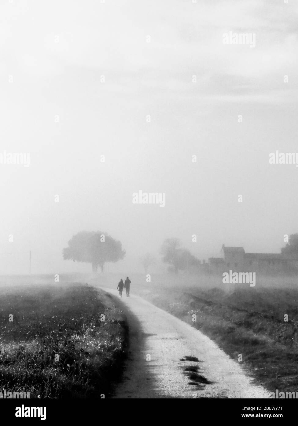 Vue sur le pays au milieu du brouillard avec un couple marchant sur une route Banque D'Images