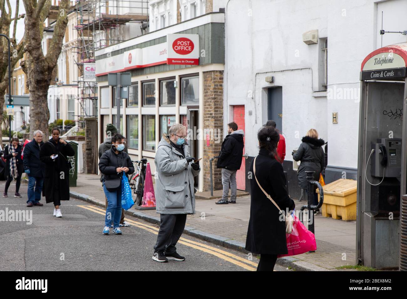 Kilburn, Londres, Royaume-Uni, 4 avril 2020 une file d'attente à l'extérieur d'un bureau de poste tandis qu'une politique de mise en place de distanciation sociale est en place pendant le virus Covid-19. Banque D'Images